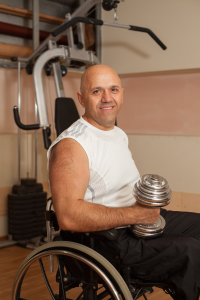 An image of a man using a wheelchair and holding a dumbbell.